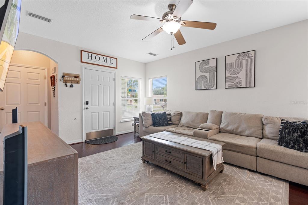 A living room features a beige sectional sofa, a wooden coffee table, and a ceiling fan — 7415 S ELLIOTT STREET, TAMPA, FL