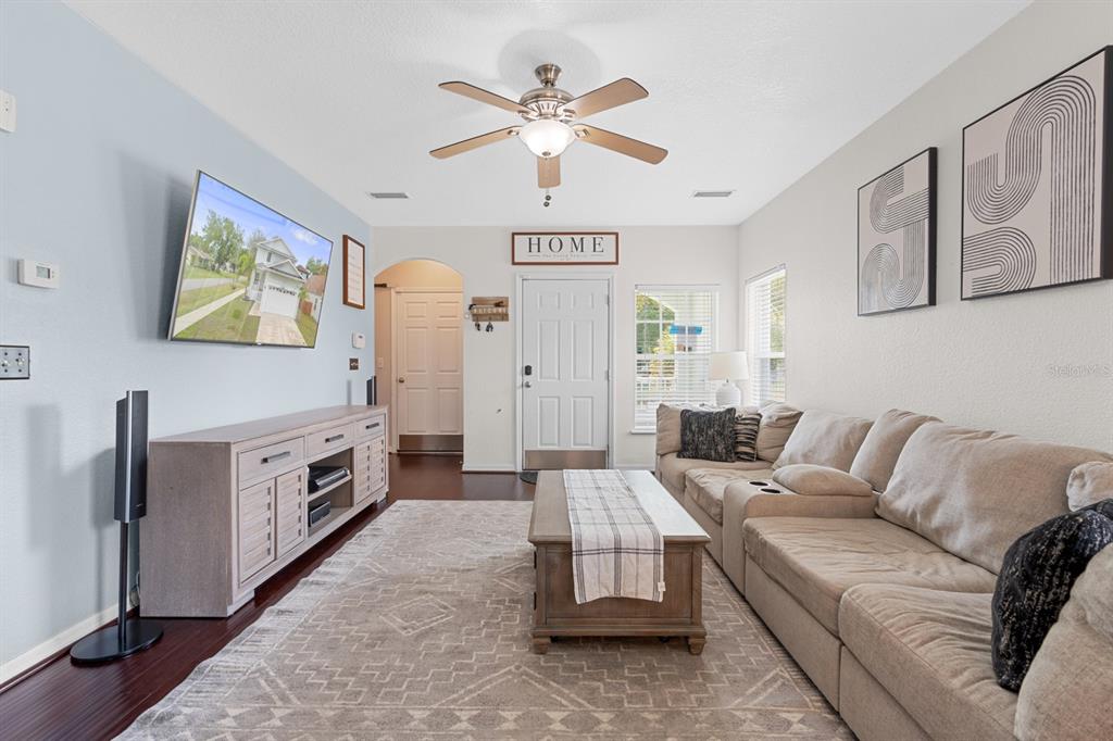 A living room features a beige sectional sofa, a wooden coffee table, and a television — 7415 S ELLIOTT STREET, TAMPA, FL