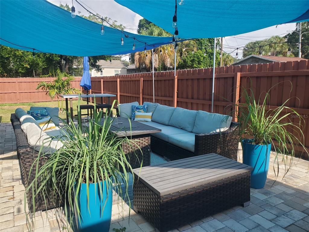 A patio features a wicker sectional sofa, a fire pit table, and a blue shade sail — 2235 20TH ST S, ST PETERSBURG, FL