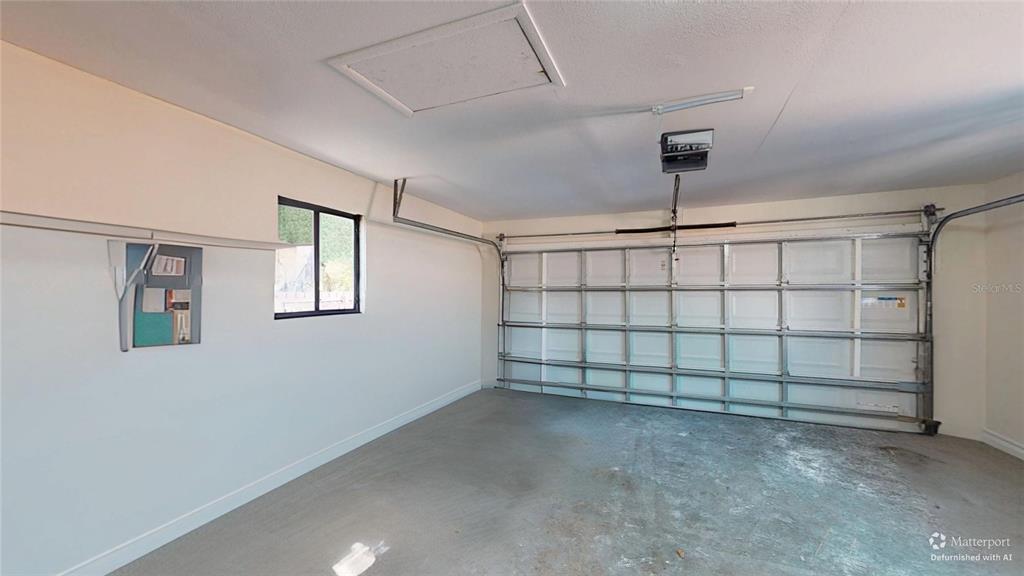 An empty two-car garage with a concrete floor, a window, and a sectional overhead door — 2235 20TH ST S, ST PETERSBURG, FL