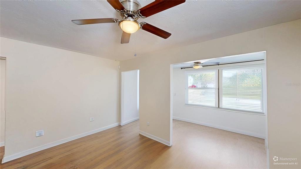 An interior view of a room with light-colored walls, wood flooring, and a ceiling fan — 2235 20TH ST S, ST PETERSBURG, FL