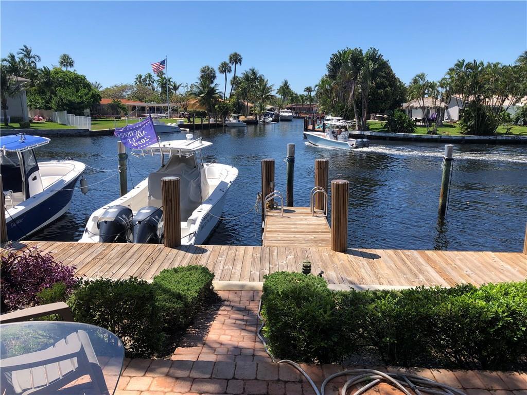 A wooden dock extends into a canal with two boats moored and another boat passing — 1351 SE 3rd Avenue, Pompano Beach FL 33060, POMPANO BEACH, FL