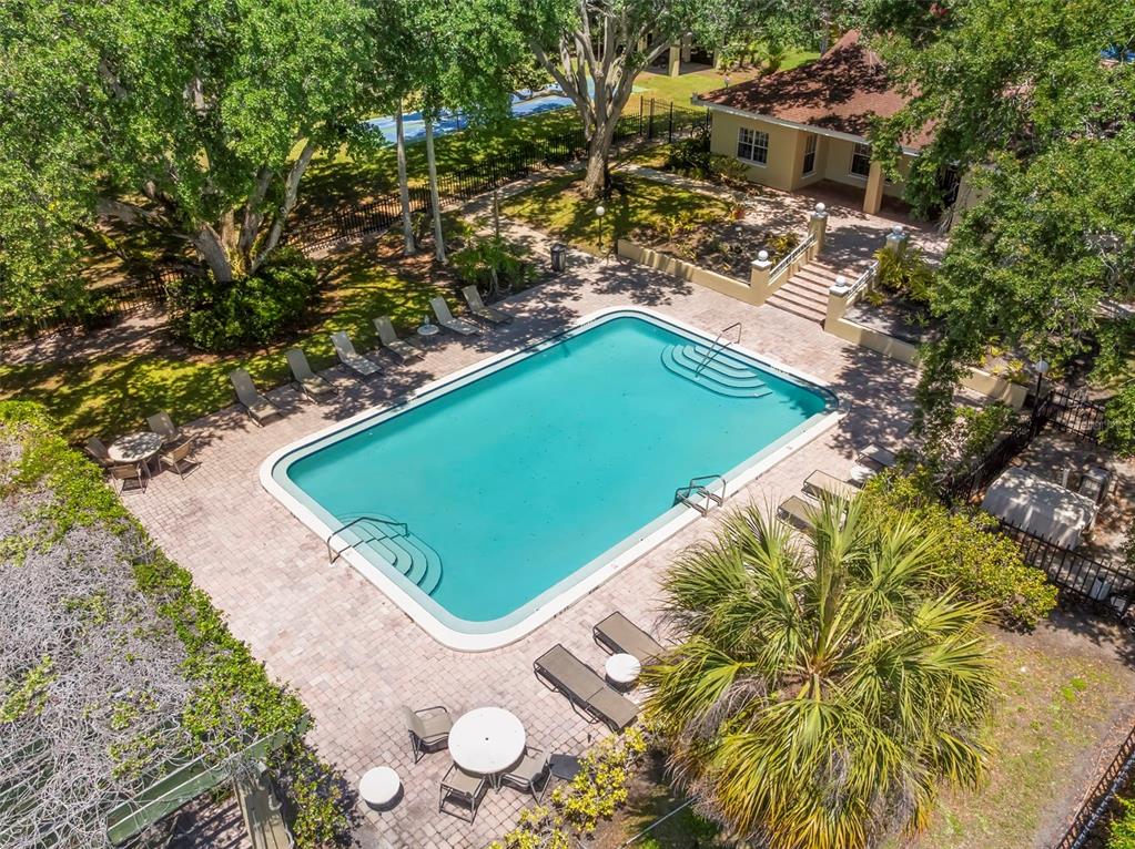 An aerial view of a rectangular swimming pool surrounded by a brick patio and trees — 2690 CORAL LANDINGS BOULEVARD UNIT 112, PALM HARBOR, FL