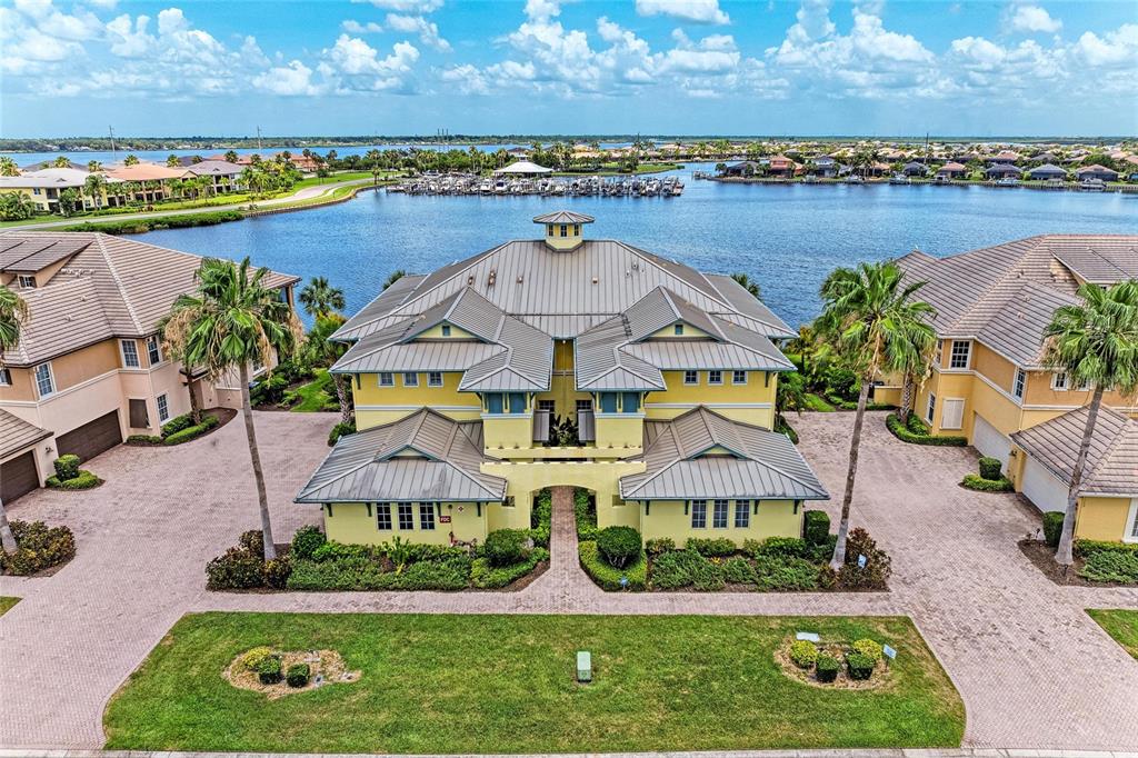 An aerial view shows a yellow multi-story building with a metal roof near a marina — 1121 RIVERSCAPE STREET UNIT 1121, BRADENTON, FL