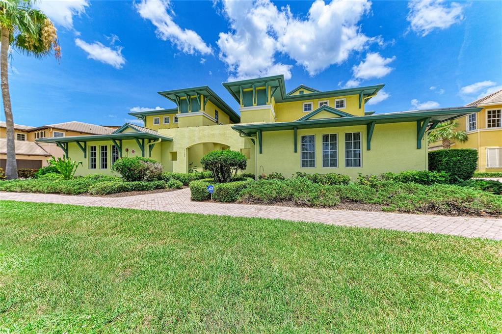 A two-story yellow house with green trim and a paved walkway under a blue sky — 1121 RIVERSCAPE STREET UNIT 1121, BRADENTON, FL