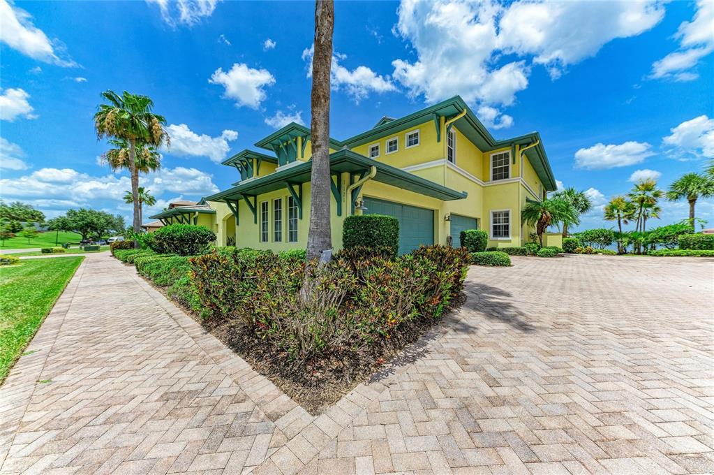 A yellow two-story house with a paved driveway and green trim under a blue sky — 1121 RIVERSCAPE STREET UNIT 1121, BRADENTON, FL