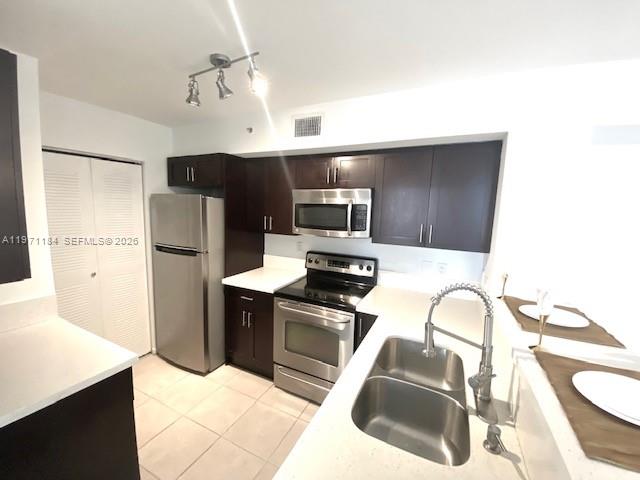 A kitchen features dark wood cabinets, stainless steel appliances, and a double-basin sink — 2061 Renaissance Blvd # 204, Miramar FL 33025, MIRAMAR, FL