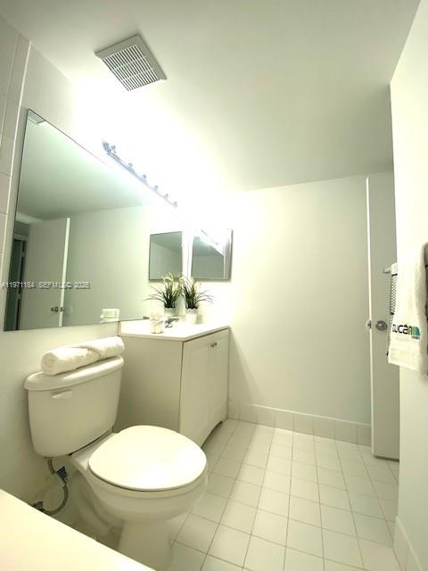 A bathroom featuring a white toilet, a vanity with a mirror, and white tile flooring — 2061 Renaissance Blvd # 204, Miramar FL 33025, MIRAMAR, FL