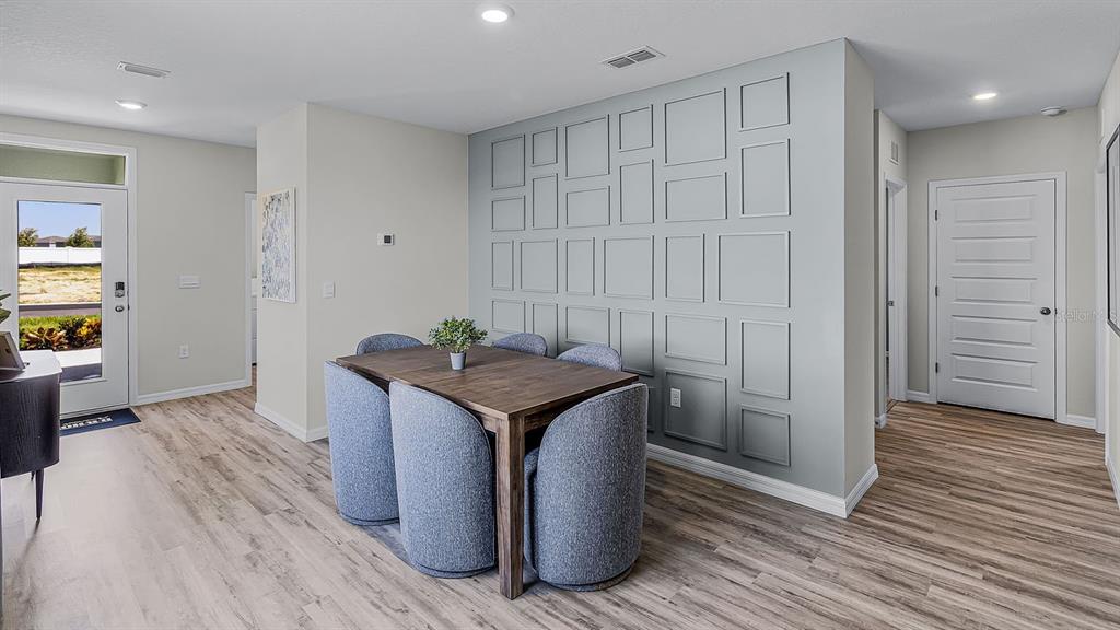 A dining area features a wooden table, blue chairs, and a gray paneled accent wall — 4052 GIORGIO DRIVE, WINTER HAVEN, FL