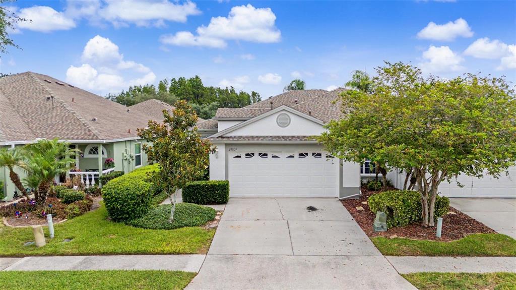 A single-story house with a two-car garage, a concrete driveway, and landscaped front yard — 19309 WEYMOUTH DRIVE, LAND O LAKES, FL