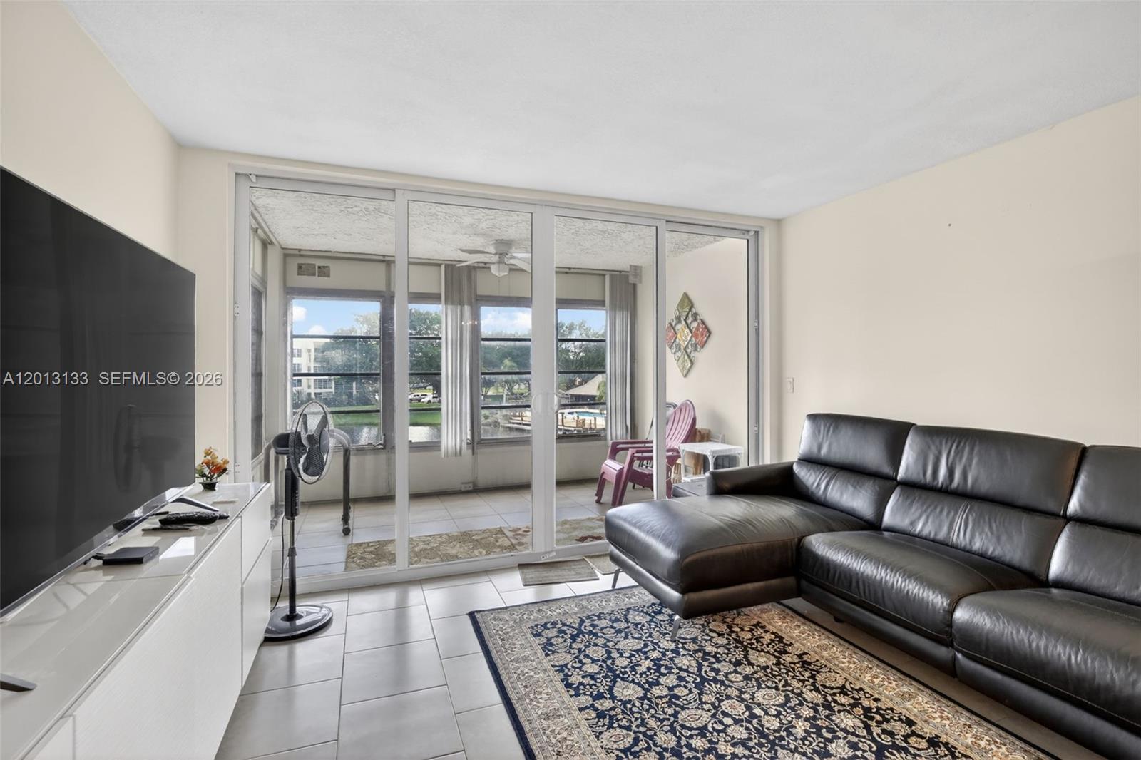 A living room with a black sectional sofa, tile floors, and sliding doors to a patio — 9330 Lagoon Pl # 307, Davie FL 33324, DAVIE, FL