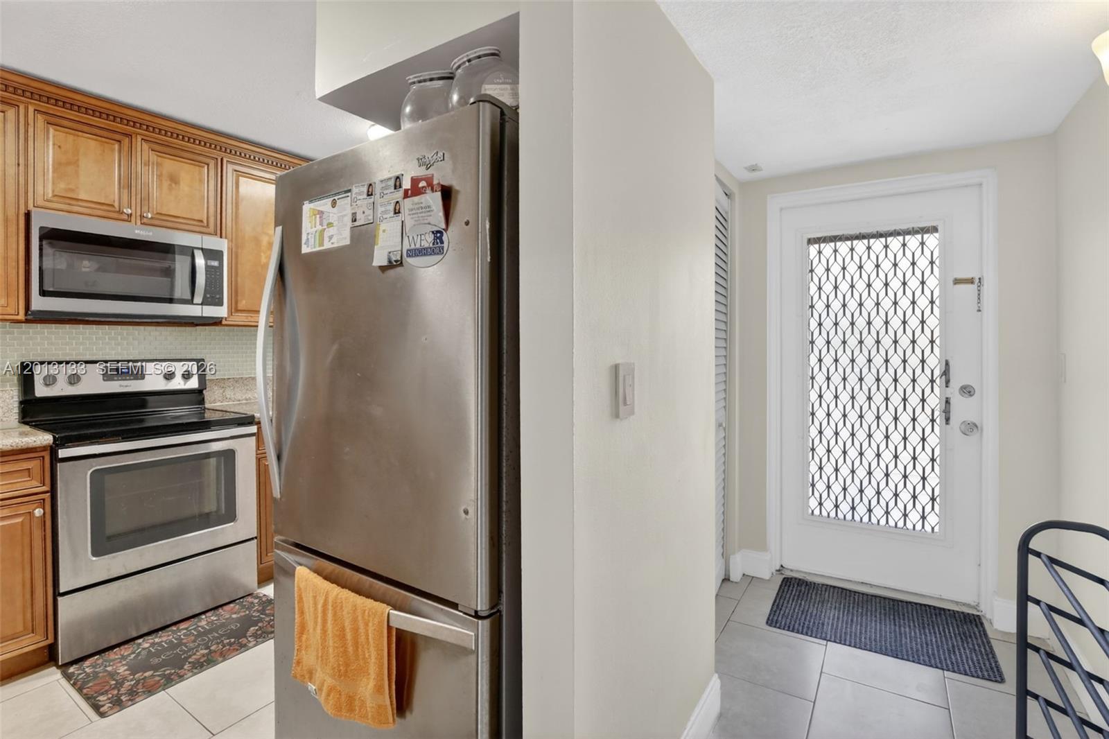 A kitchen features stainless steel appliances, wooden cabinets, and a door leading to the outside — 9330 Lagoon Pl # 307, Davie FL 33324, DAVIE, FL