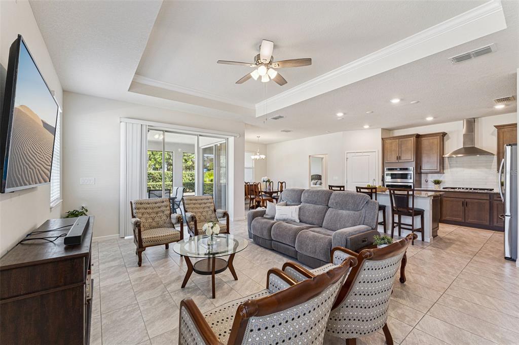 An open-concept living room and kitchen featuring tile floors, a tray ceiling, and neutral walls — 6237 CITRUS GROVE COURT, ST CLOUD, FL