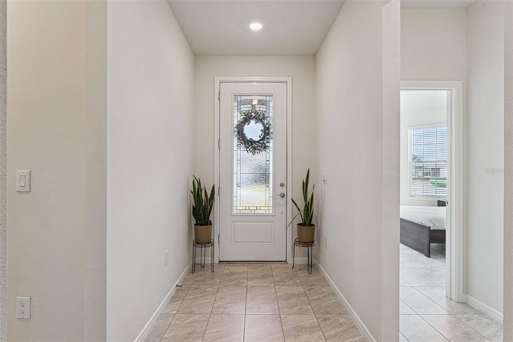A tiled entryway features a white front door with a glass insert and two potted plants — 6237 CITRUS GROVE COURT, ST CLOUD, FL