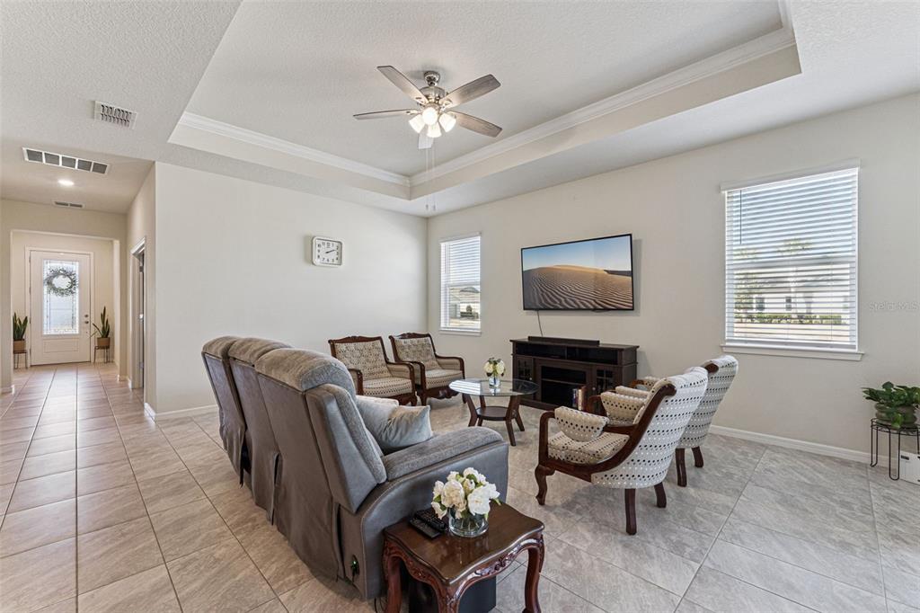 A living room with tile floors, a tray ceiling, a ceiling fan, and a television — 6237 CITRUS GROVE COURT, ST CLOUD, FL