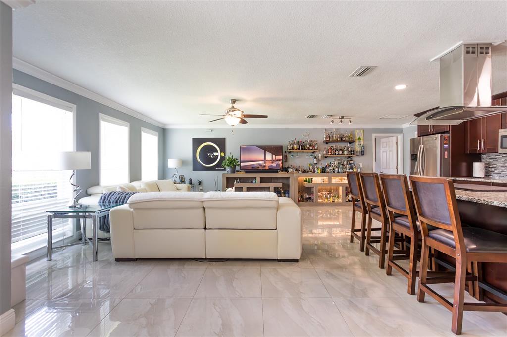 An open-concept living room features a white sofa, a home bar, and tile flooring — 2198 OAK GROVE DRIVE, CLEARWATER, FL