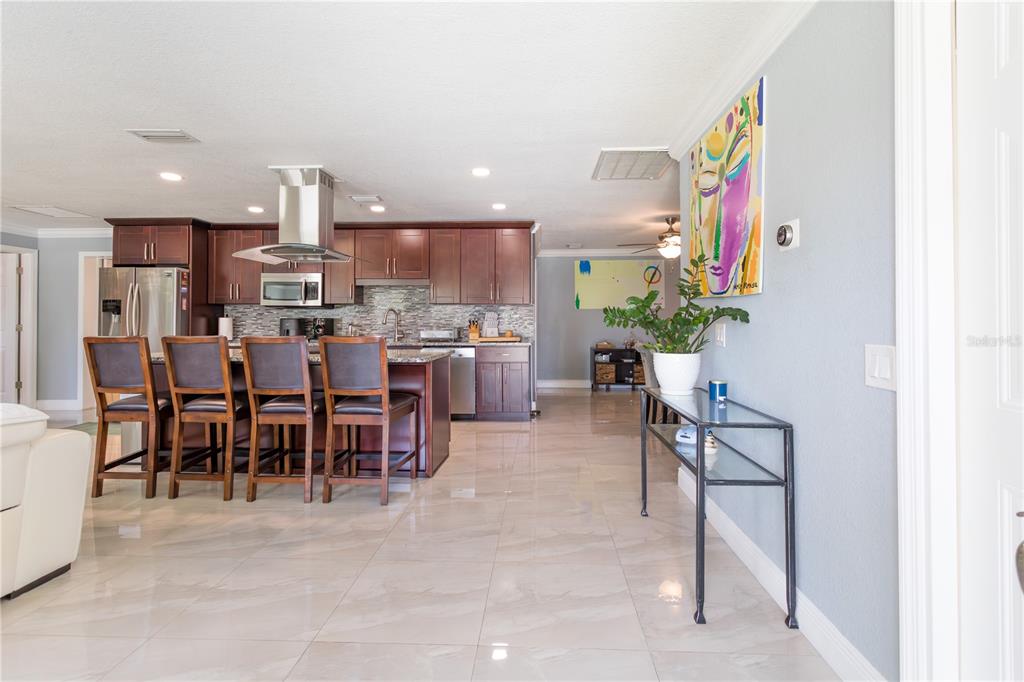 A kitchen with dark wood cabinets, a granite island, and bar seating on tiled floors — 2198 OAK GROVE DRIVE, CLEARWATER, FL