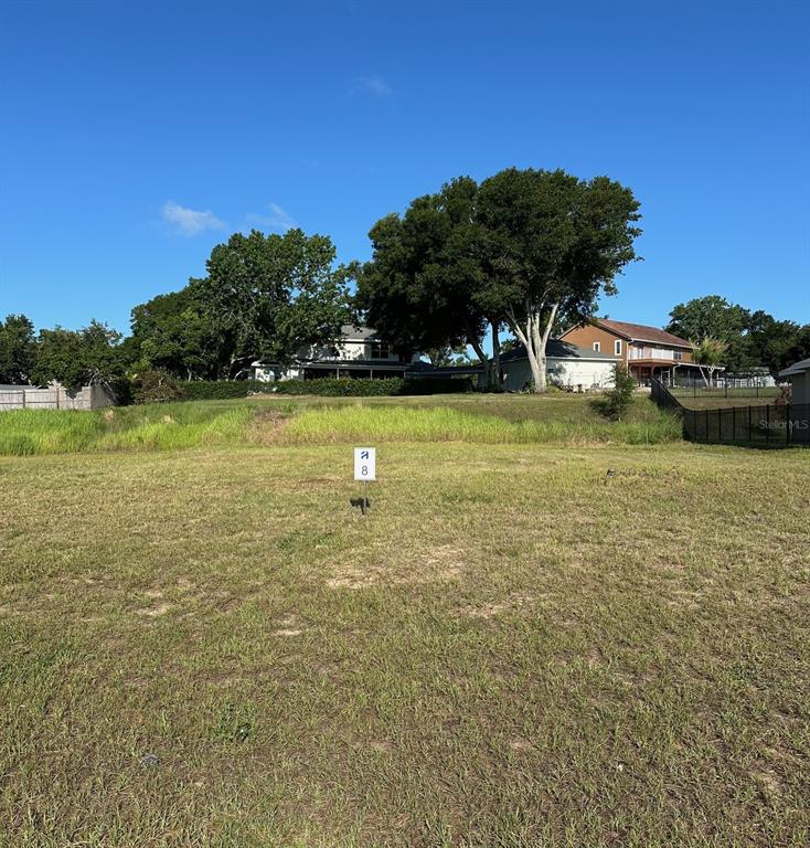 A vacant grassy lot features a sign marked with the number 8 — 11631 MATANILLA DRIVE, CLERMONT, FL