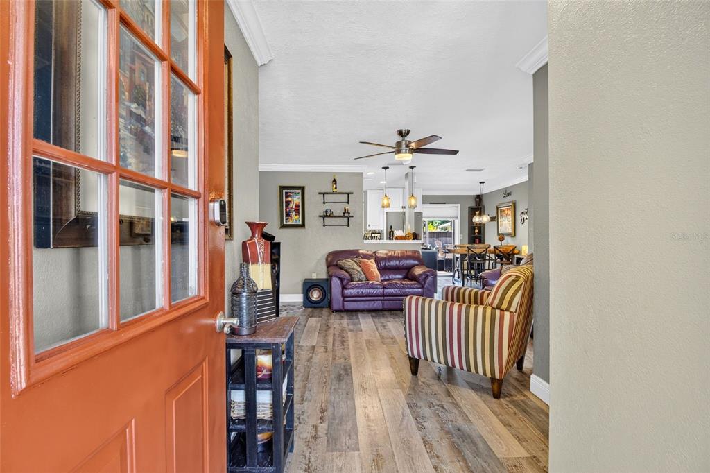 An entryway opens into a living room with wood-look flooring and a purple leather sofa — 1018 KENSINGTON STREET, PORT CHARLOTTE, FL