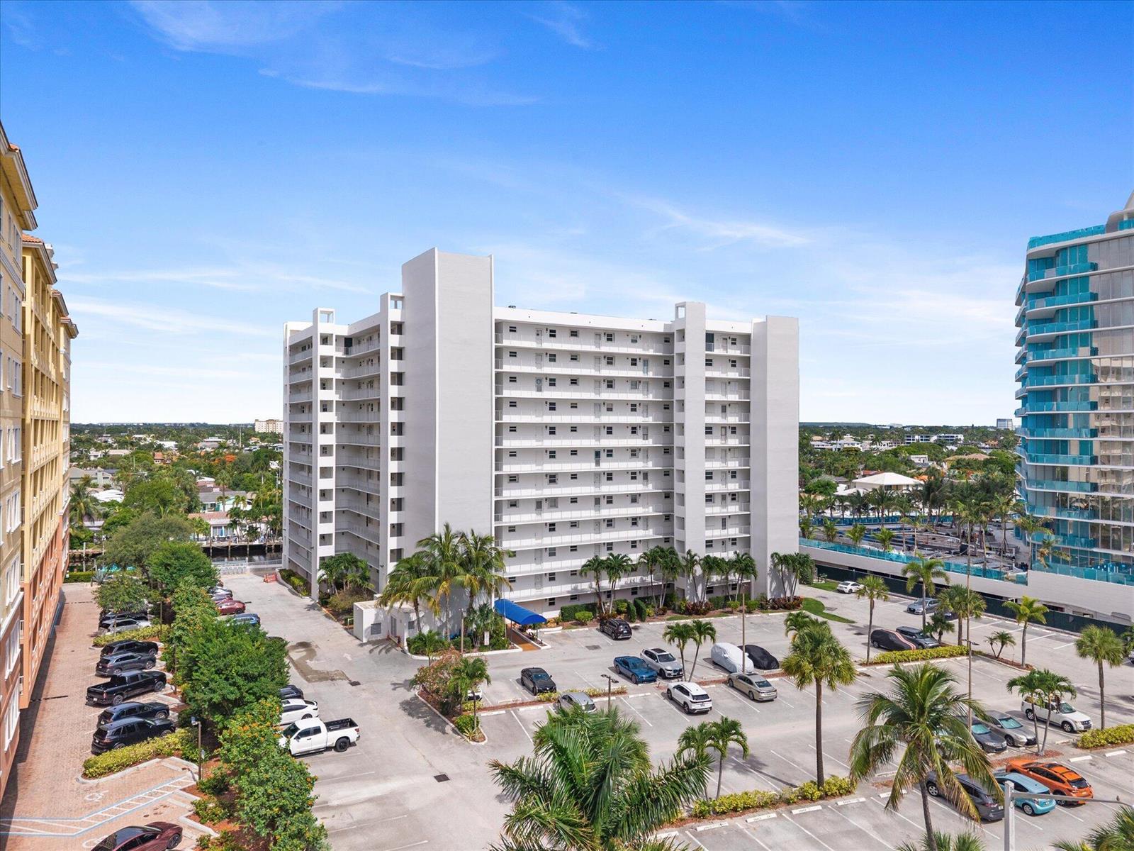 An elevated view shows a multi-story white apartment building with a parking lot below — 1391 S Ocean Boulevard # 206, Pompano Beach FL 33062, POMPANO BEACH, FL