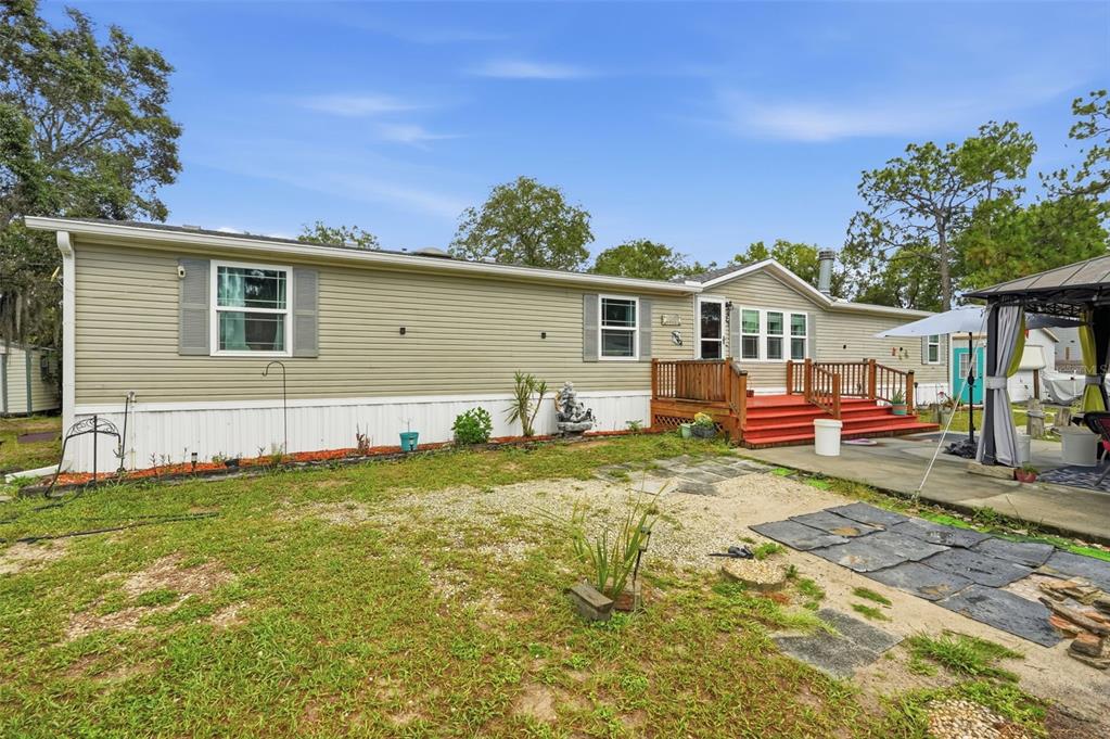 A single-story manufactured home with light green siding, a red wooden deck, and a gazebo — 825 N GRIFFITH AVENUE, CRYSTAL RIVER, FL