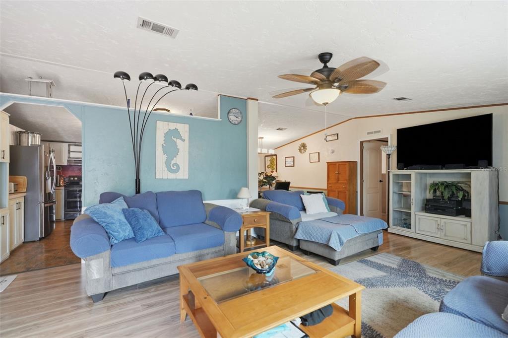 A living room features blue walls, a blue sofa, a chaise lounge, and a ceiling fan — 825 N GRIFFITH AVENUE, CRYSTAL RIVER, FL