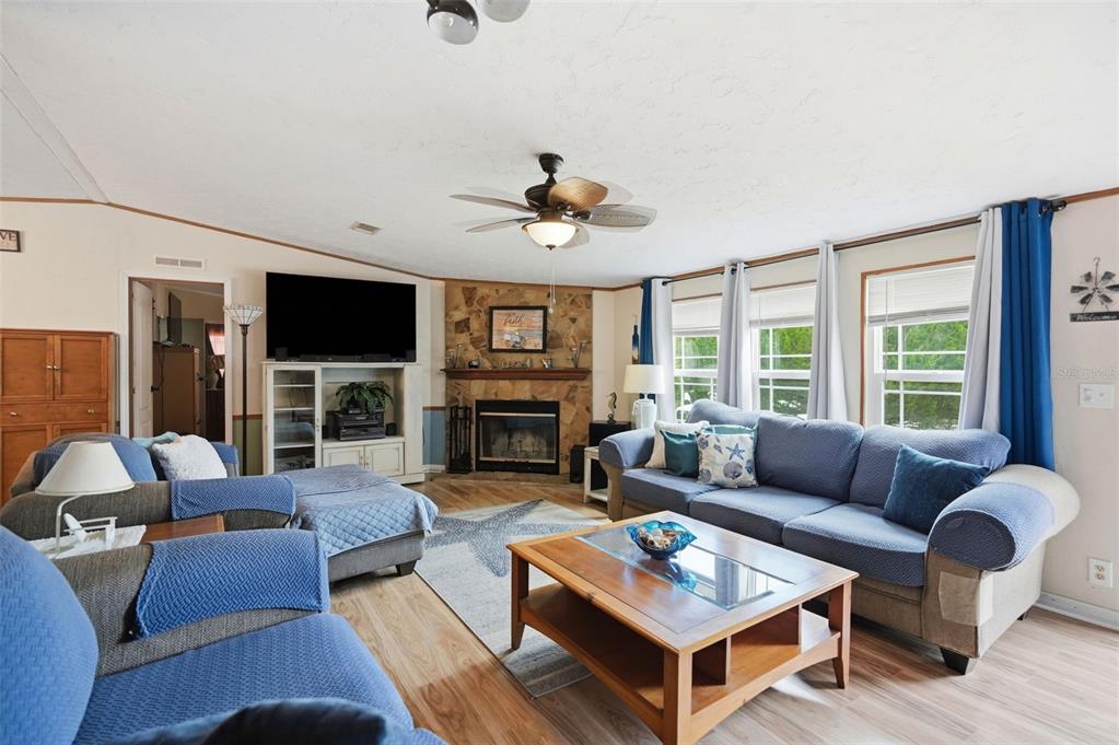 A living room features a stone fireplace, blue sofas, and a wooden coffee table — 825 N GRIFFITH AVENUE, CRYSTAL RIVER, FL