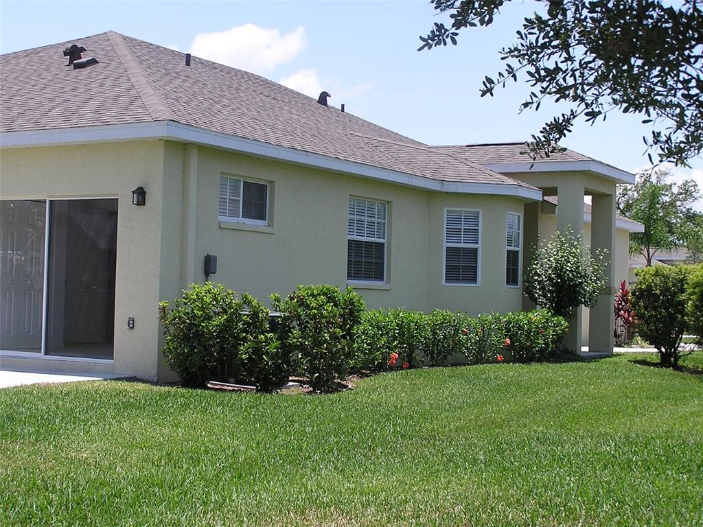 A beige house exterior features a sliding glass door, several windows, and landscaped shrubbery — 412 W 28TH STREET UNIT 0, PALMETTO, FL