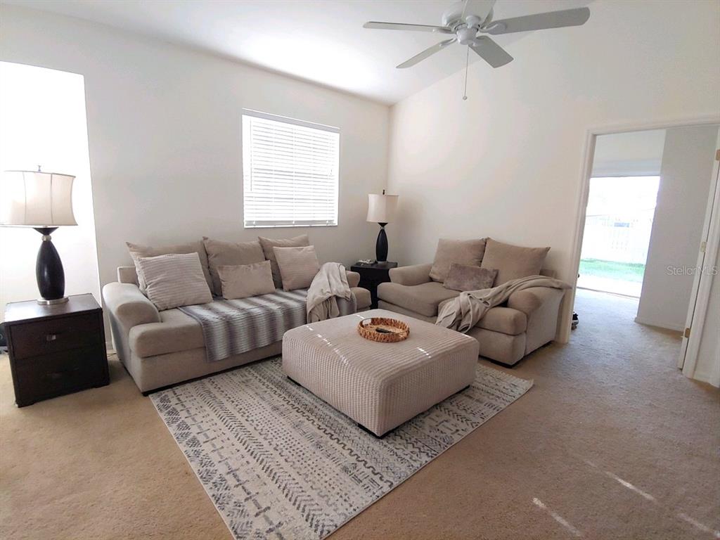 A living room features two beige sofas, a square ottoman, and a patterned area rug — 412 W 28TH STREET UNIT 0, PALMETTO, FL