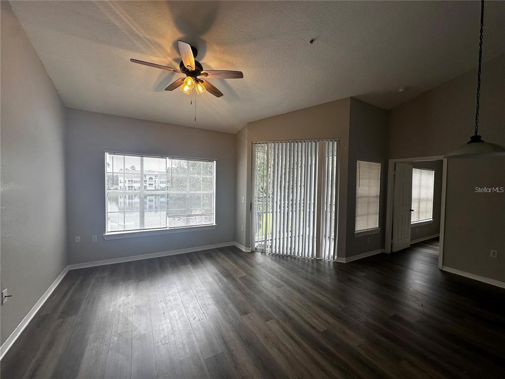 A living room with wood-look flooring, a ceiling fan, and sliding glass doors to a patio — 2314 MIDTOWN TERRACE UNIT 1125, ORLANDO, FL