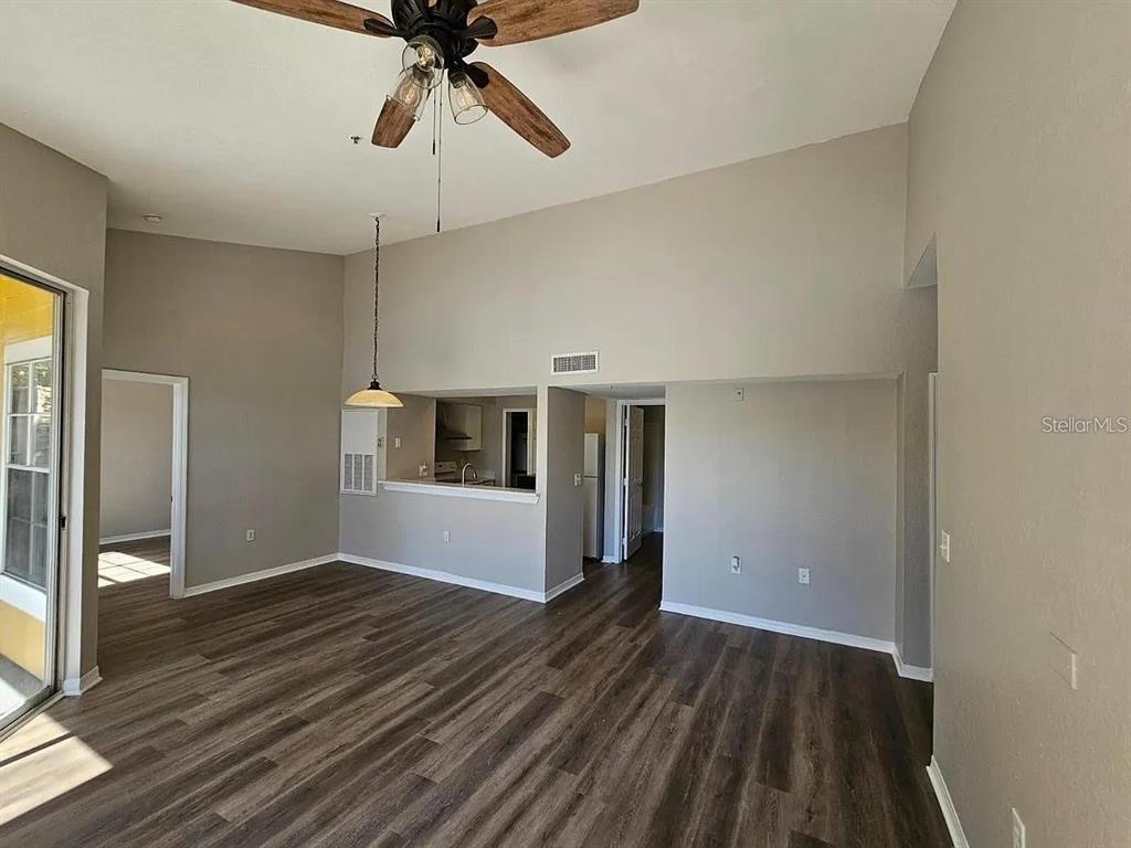 An open-concept living area features wood-look flooring, a ceiling fan, and a kitchen pass-through window — 2314 MIDTOWN TERRACE UNIT 1125, ORLANDO, FL