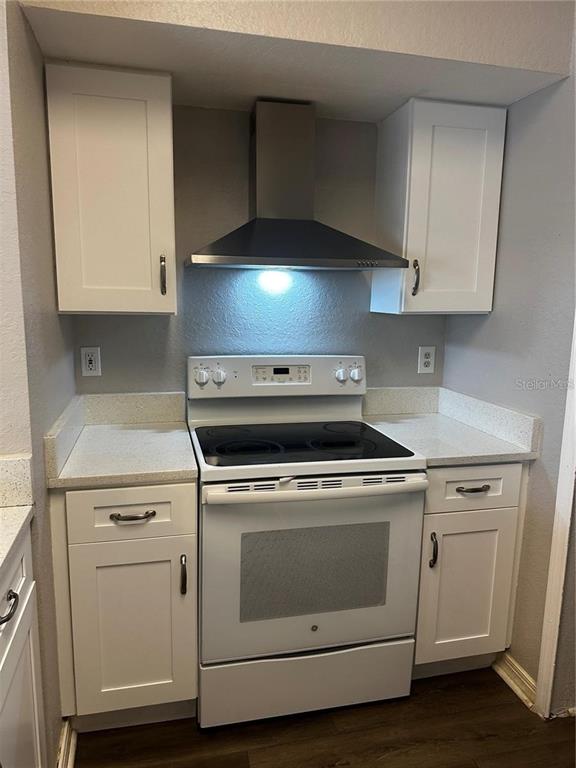 A kitchen features white cabinets, a stainless steel range hood, and a white electric stove — 2314 MIDTOWN TERRACE UNIT 1125, ORLANDO, FL