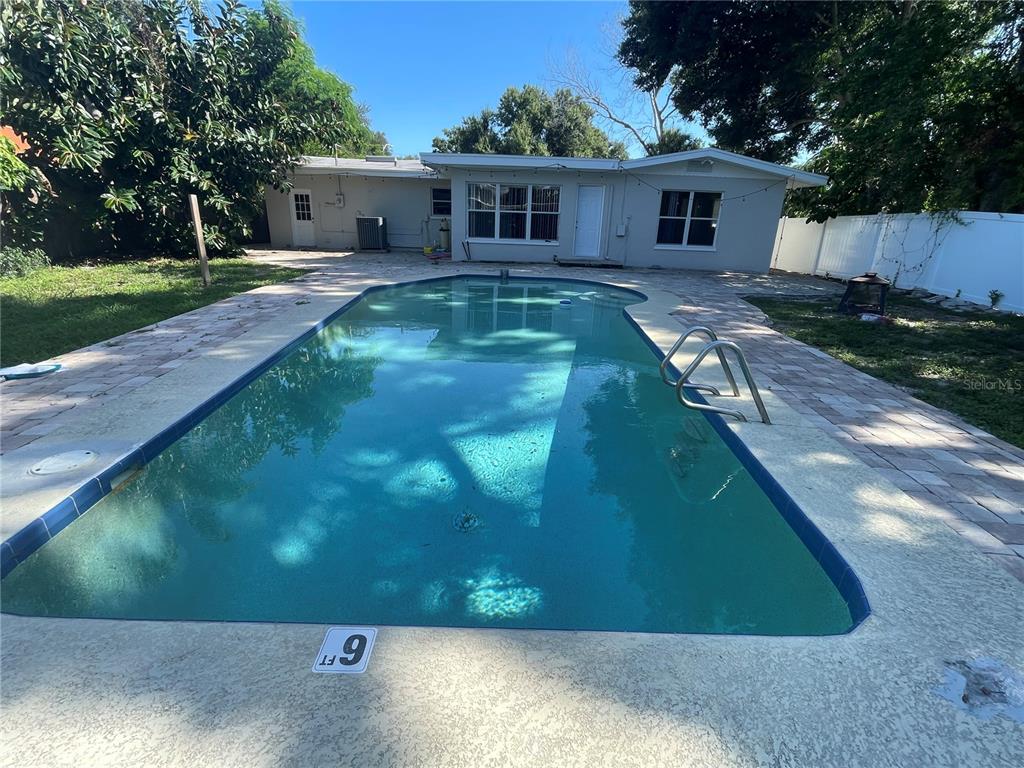 A backyard features a large swimming pool with a six-foot depth marker and a house — 6219 12TH AVENUE S, GULFPORT, FL