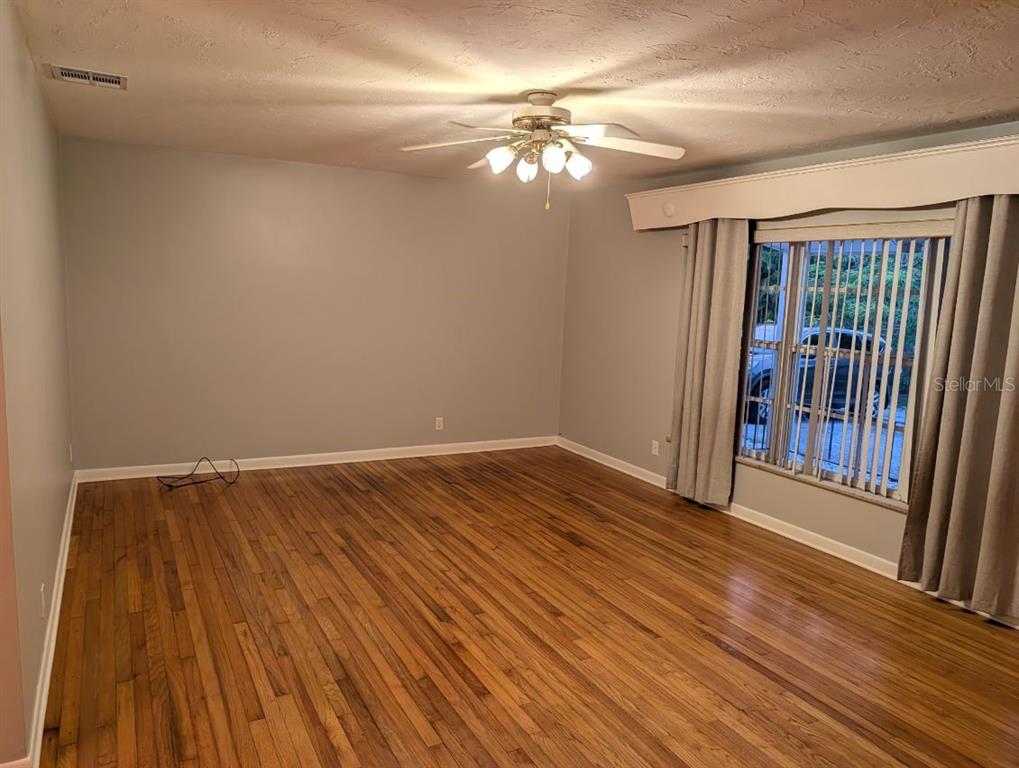 An empty room with hardwood floors, a ceiling fan, and a window with curtains — 6219 12TH AVENUE S, GULFPORT, FL