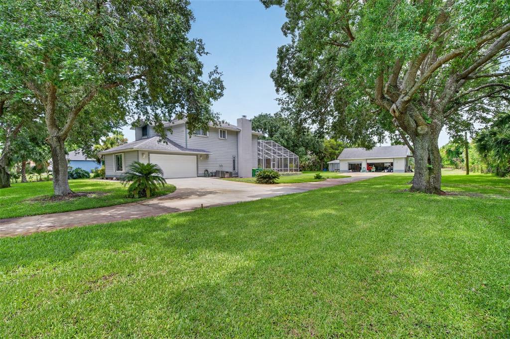 A two-story house with a detached garage and a screened-in pool area on a lawn — 3247 DALHI STREET, COCOA, FL