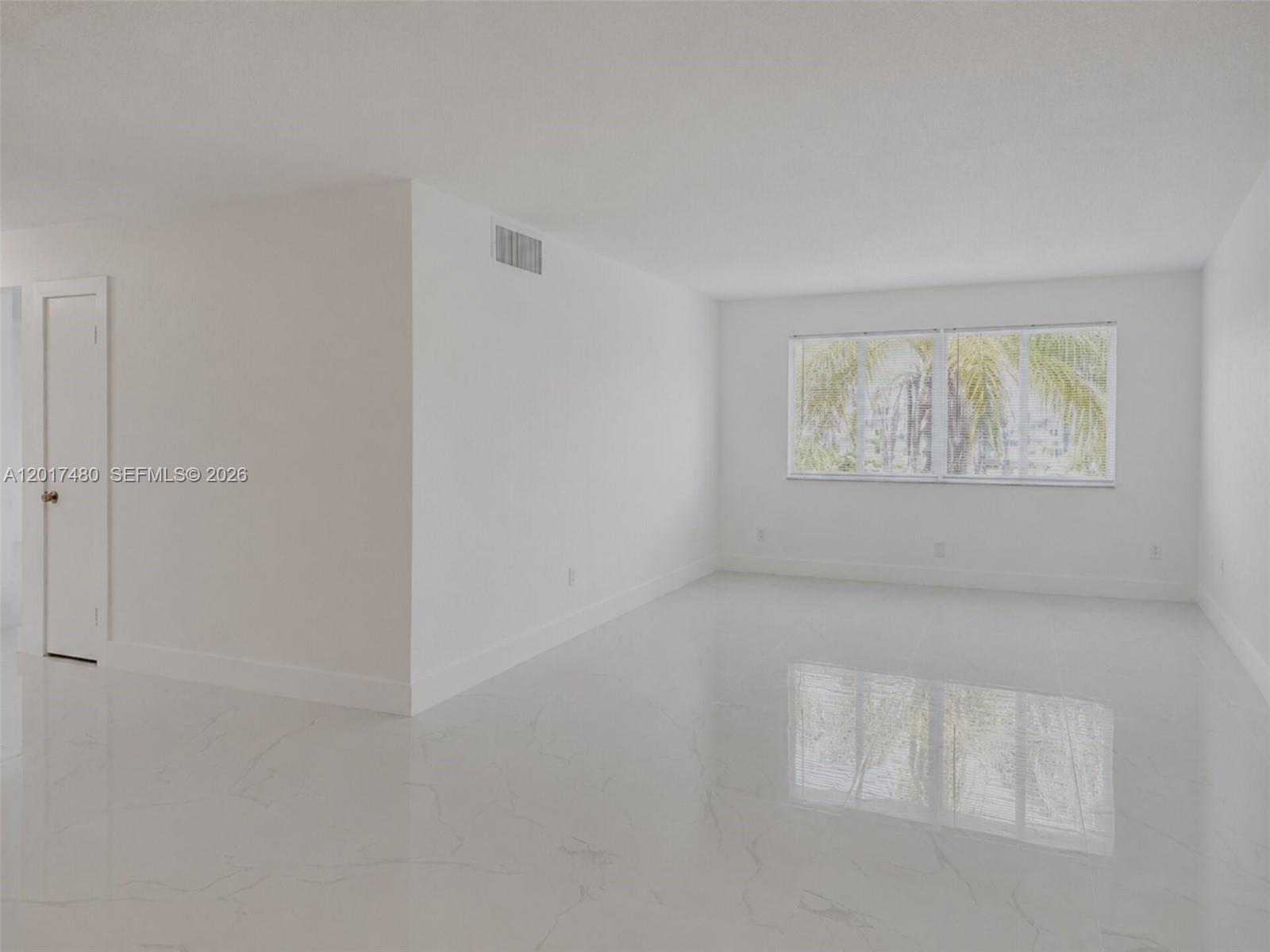 A bright, empty room features white walls, glossy marble-style tile flooring, and a window — 14830 Naranja Lakes Blvd, Homestead FL 33032, HOMESTEAD, FL