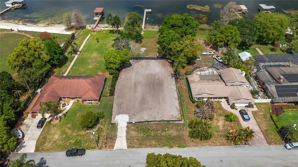 An aerial view shows a vacant rectangular lot situated between two houses near a lake — 2815 TRENTWOOD BOULEVARD, BELLE ISLE, FL