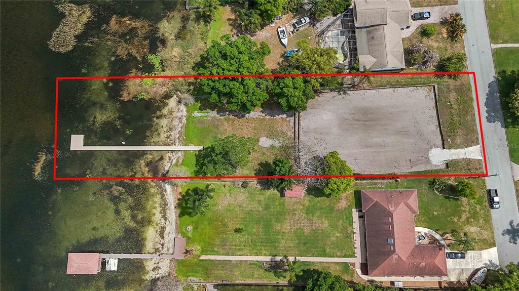 An aerial view shows a vacant, rectangular waterfront lot with a dock extending into the lake — 2815 TRENTWOOD BOULEVARD, BELLE ISLE, FL