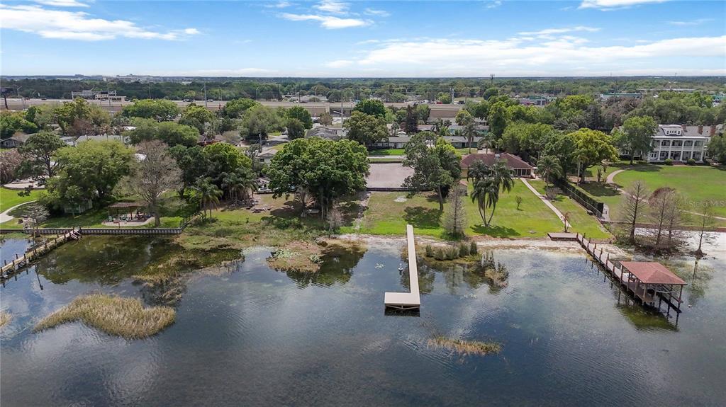 An aerial view shows a grassy waterfront property with a long dock and boat house — 2815 TRENTWOOD BOULEVARD, BELLE ISLE, FL