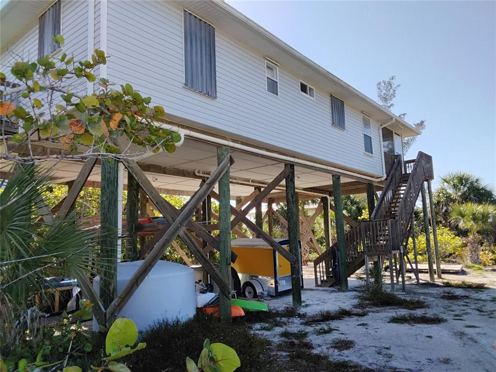 An elevated house on wooden pilings with a staircase leading to the main level — 91 GASPARILLA WAY, PLACIDA, FL