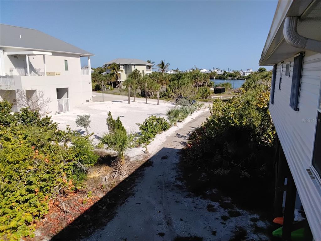 An elevated view shows a sandy lot, tropical vegetation, and a nearby waterway — 91 GASPARILLA WAY, PLACIDA, FL