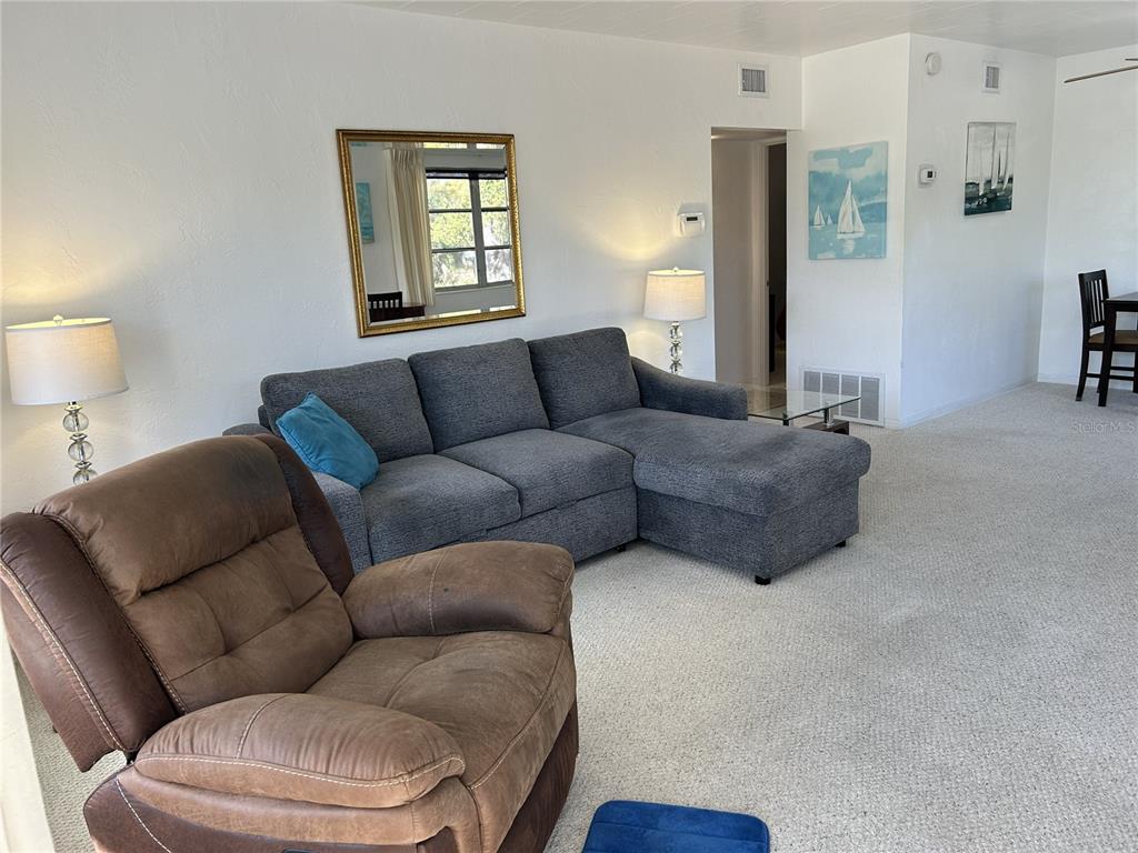 A living room features a grey sectional sofa, a brown recliner, and white walls — 4154 57TH STREET N UNIT 274, KENNETH CITY, FL