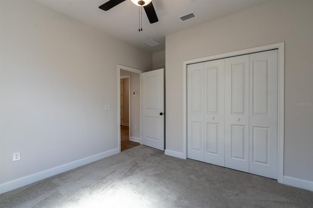 A bedroom with gray carpet, light walls, a ceiling fan, and a white closet door — 12581 NW 159TH WAY, ALACHUA, FL