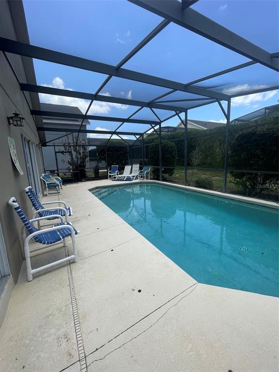 A screened-in swimming pool area features a concrete deck and several outdoor chairs — 16705 FRESH MEADOW DRIVE, CLERMONT, FL