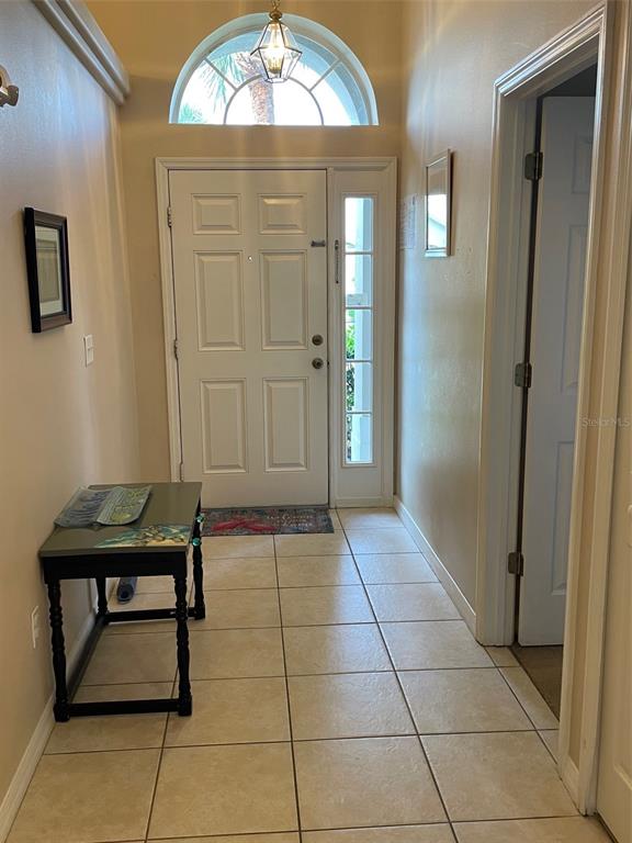 An entryway features a white front door with a sidelight, tile flooring, and a console table — 16705 FRESH MEADOW DRIVE, CLERMONT, FL