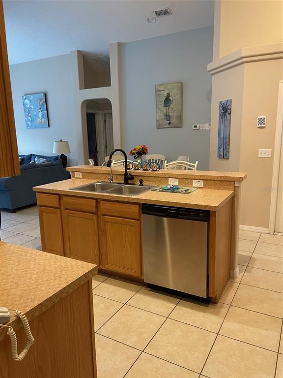 A kitchen island features a double sink, stainless steel dishwasher, and light-colored laminate countertops — 16705 FRESH MEADOW DRIVE, CLERMONT, FL