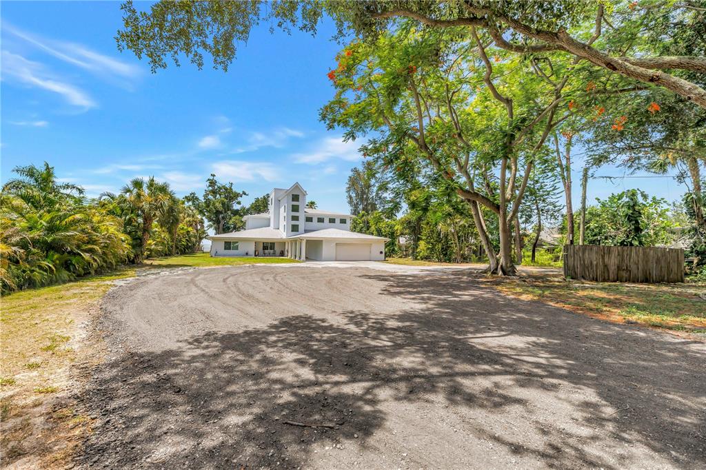A white multi-story house with a garage sits at the end of a dirt driveway — 2280 PINELLAS POINT DRIVE S, ST PETERSBURG, FL