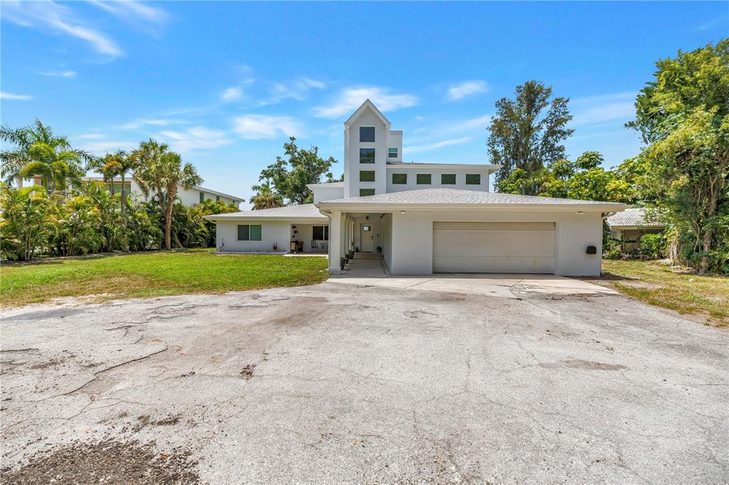 A white house with a prominent vertical tower and an attached garage sits on a lot — 2280 PINELLAS POINT DRIVE S, ST PETERSBURG, FL