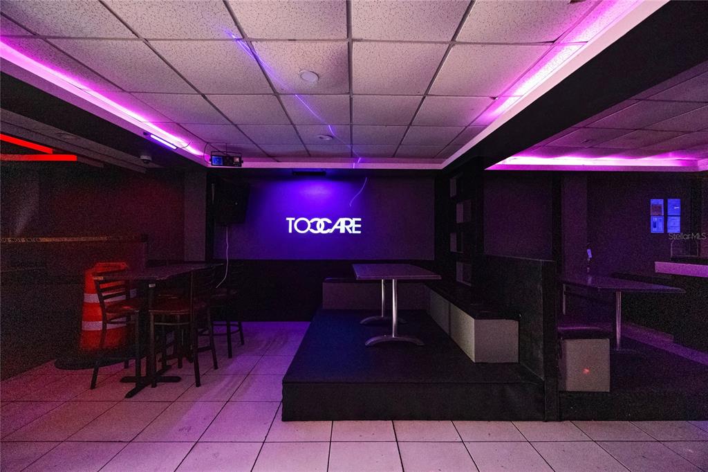 A dimly lit room features tiled flooring, a raised platform with tables, and purple accent lighting — 239 C ELEANOR ROOSEVELT, SAN JUAN, PR