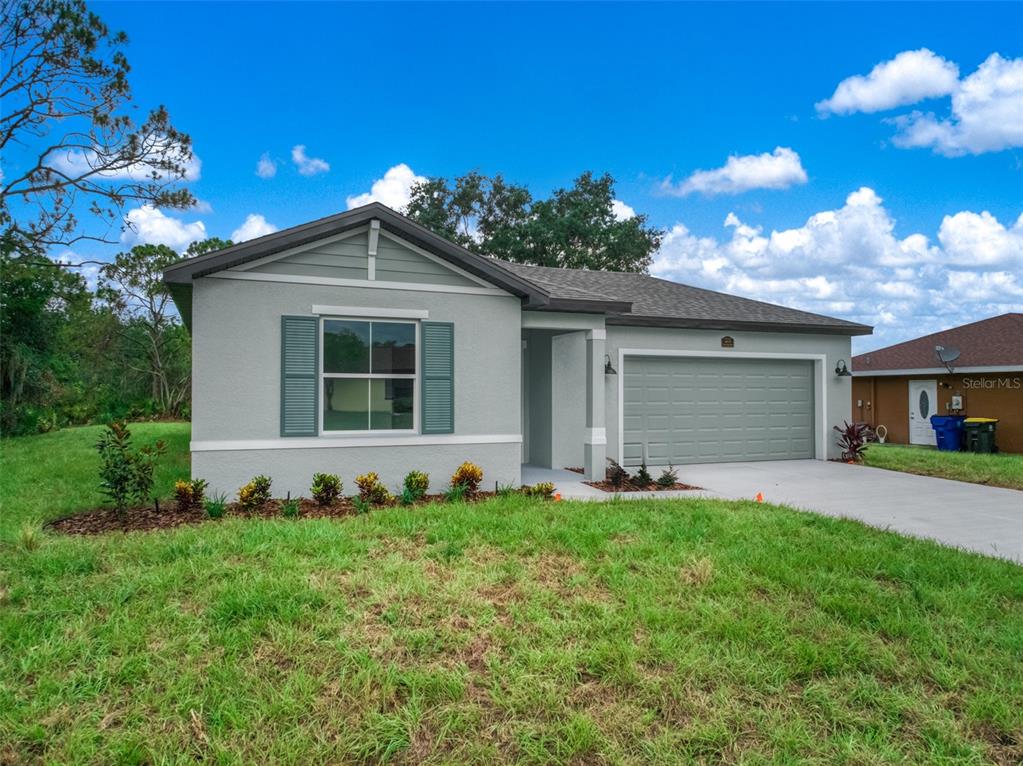 A single-story house with a gray stucco exterior, green shutters, and a two-car garage — 4015 FONSECA AVENUE, SEBRING, FL